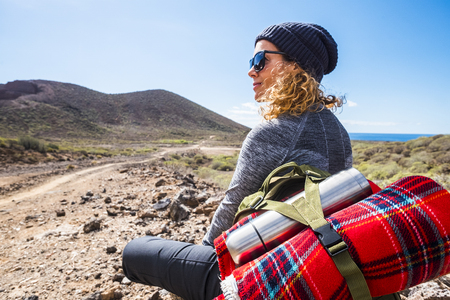 People and trekking backpack travel adventure activity - blonde woman sit down and rest looking at the beautiful scenic landscape with sea and valley enjoying the hiking leisure alone - alternative lifestyleの写真素材