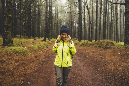 Happy hiker travel in the high trees wild beautiful forest with backpack - enjoying natural wood for pretty blonde young woman - adventure and trekking conceptの写真素材