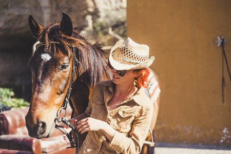 Woman and horse. Couple of friends enjoying the sunset for ride. People with cowboy hatの写真素材