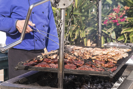 Close up of outdoor big barbecue bbq grill for restaurant or catering business concept - fresh meat and tasty food for people - man cooking outdoor with fireの写真素材