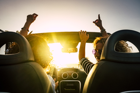 People joy and happy driving and traveling for summer holiday vacation and outdoor leisure activity with convertivle car laughing and dancing like crazy - sunlight in the glass and travel conceptの写真素材