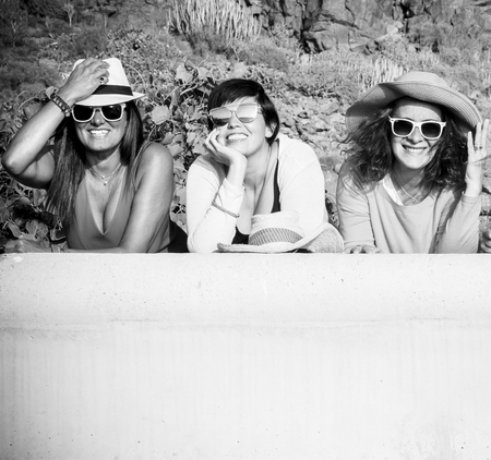 Black and white picture with three cheerful happy caucasian people young women smiling and looking at the camera in outdoor friendship activityの写真素材