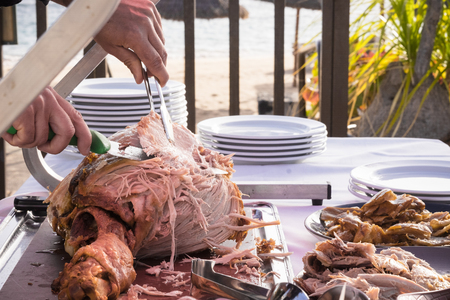 Outdoor celebration with restaurant or catering concept and chef man cutting and serving a tasty nice big turkey - beach in backgroundの写真素材