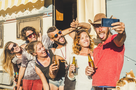 Alternative millennial young caucasian people group of friends taking selfie picture outside in sunny day outdoor leisure activity celebrate together with beer and lot of fun and laughsの写真素材