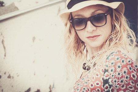Fashion young beautiful girl middle age portrait in vintage filter colors - fashion style for young lady with sunglasses and hat and dress with flowersの写真素材