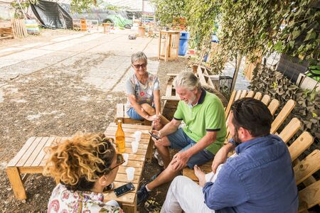 caucasian family in relationship and friendship sitting outdoor in a natural place made with recycled wood. from grandfthers to mother to son. old, middle age and teenager all together enjoying the dayの写真素材