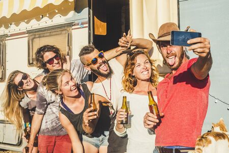 Alternative millennial young caucasian people group of friends taking selfie picture outside in sunny day outdoor leisure activity celebrate together with beer and lot of fun and laughsの写真素材