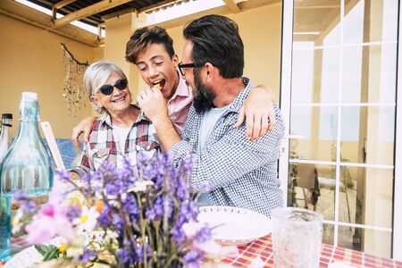 Three diverse generations family caucasian people ocncept eating lunch together - grandmother, son and grandson have fon with love and friendship outdoor at homeの写真素材