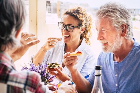 People having fun together during lunch in friendship - mixed ages woman and an eating in family activity - caucasian adults laugh and smile for nice activityの写真素材