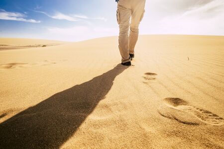 Travel and explore people concept with man viewed from back walking in tha sand of the desert dunes alone under the sunset - summer holiday vacation and nature outdoor in scenic placeの写真素材
