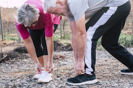 Active senior people caucasian couple doing exercises outdoor in sunny day - leisure activity for healthy retired old mature man and woman having fun together in the natureの写真素材
