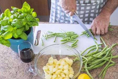 Closeup of man cutting vegetables at home cooking the lunch or dinner for family or friends - healthy lifestyle concept with vegetarian or vegan lifestyleの写真素材
