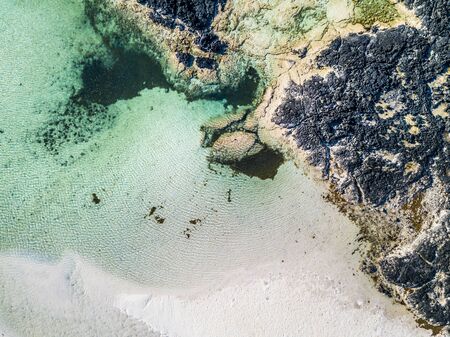 Vertical aerial view of white lagoon sand beach and clear tourquoise water - resort beautiful summer holiday destination with ocean and rocks - paradise and relax concept with natureの写真素材