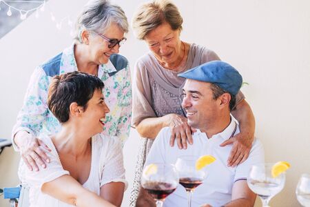 Family people cheerful portrait with mothers and son hugging and enjoying the friendship - mixed generations from old senior to adults together drinking red wine and cocktailsの写真素材