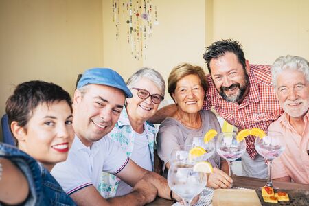 Cheerful group of mixed ages friend portrait - young adult and senior caucasian people smile at the camera and hug eachother having fun together - focus on last manの写真素材
