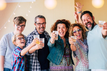Group of people caucasian men and women different ages from children to teenager to adults enjoy and celenrate together toasting with glasses and having a lot of fun for friendshipの写真素材