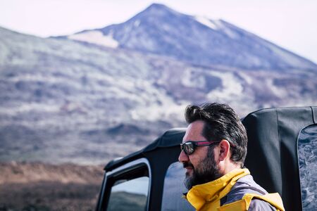 Handsome adult caucasian man with beard and sunglasses and mountain in background - travel adventure people outdoor concept with off road car and equipment - active lifestyleの写真素材