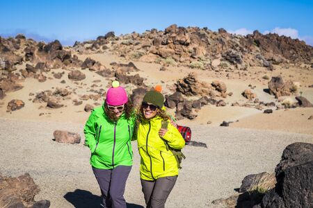 People have fun in outdoor leisure sport activity at the mountsin - couple of cheerful women with backpack on the mountain walking and doing trekking day together - travel and healthy vacationの写真素材