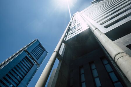 Blue cold tones colors of skyscrapers with sunlight - looking up perspective, city view of offices and financial district with bank and insurance people at workの写真素材