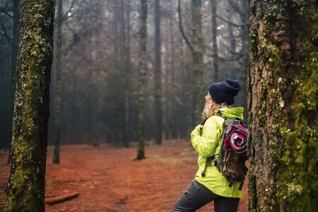 Healthy sporty woman enjoying the outdoor leisure activity with a backpack and trekking equipment in the middle of a rainy wild forest - people with alternative lifestyle and adventure needの写真素材