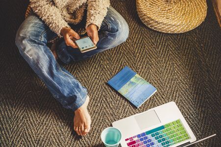 Technology and modern devices phone and laptop concept with woman using cellular and notebook on the floor at home - people internet social addicted or at work out of office in freelance free modeの写真素材