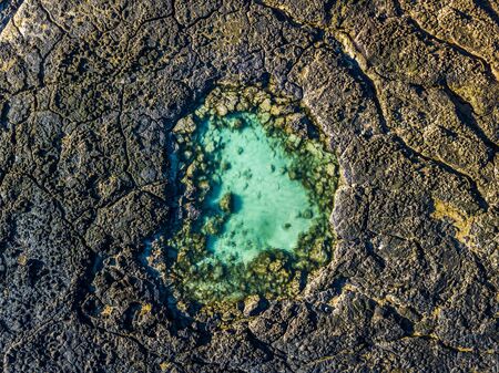 Blue natural swimming pool in the middle of black vulcanic rocks - green lagoon ocean water - aerial top view - beauty of planet and earth's day concept - summer holiday vacation destinationの写真素材