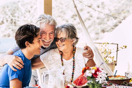 Portrait of people caucasian family with teen and grandfathers smiling and having fun together at home or restaurant eating food - concept of diversity and mixed ages with seniorの写真素材