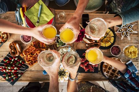 Group of friend mixed ages  generations from children to adult have fun togeter with food and drinks - aerial top view of table and people toasting together in friendship - home or restaurant conceptの写真素材
