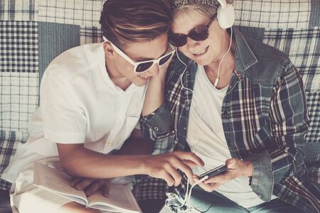 couple young and old grandmother and teenager nephew family time together listen music with earphones and enjoy the day. Happy family and generations different ages conceptの写真素材