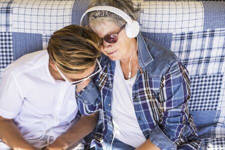 couple young and old grandmother and teenager nephew family time together listen music with earphones and enjoy the day. Happy family and generations different ages conceptの写真素材