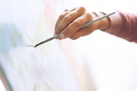 Closeup of woman hand painting an art wallpaper with old style - creativity and artist at work for hobby or job - colors and background conceptの写真素材