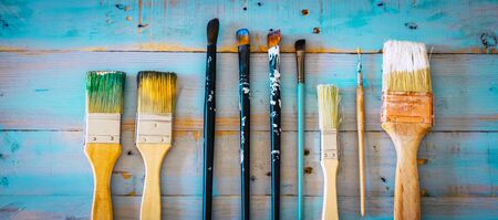 Set of paint brushes for artist and decorator on a blue wooden table - concept of art and work at home - above view - dirty of colors for a beautiful nice backgroundの写真素材