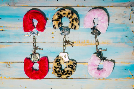 Fur handcuffs sex play for modern free alternative couple on a wooden background - concept of love...
