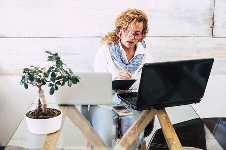 Business woman at office with double laptop workstation - concept of stress and work for people - home free job  and beautiful people - modern caucasian female with computers and technologyの写真素材