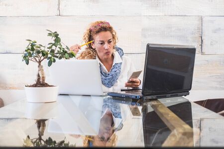 Business woman at office with double laptop workstation - concept of stress and work for people - home free job  and beautiful people - modern caucasian female with computers and technologyの写真素材