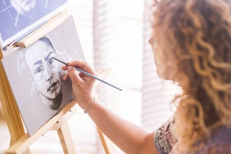 Art, creativity and people concept - caucasian closeup of woman hand painting and drawing a portrait at home in black and white - artistic leisure activity - brush on canvas to createの写真素材