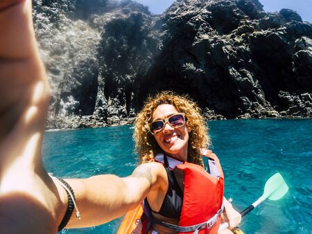 Cheerful people happy smiling female take selfie picture with kayak having outdoor leisure sport activity in the blue ocean water - concept of hapiness in summer holiday vacationの写真素材