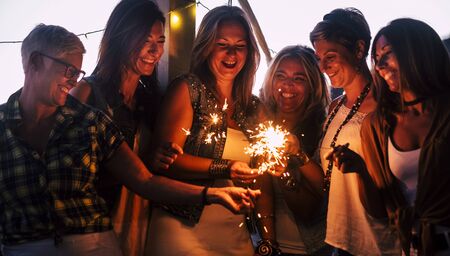 Friends celebrating together with love and friendship concept - group of females people smile and have fun by night with sparklers and laughs -   new year eve party celebrationの写真素材