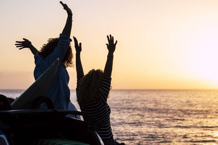 Happiness and successful concept with couple of women young friends enjoy the sunset on holiday summer vacation - joyful and people in outdoor travel leisure activity - ocean and sun backgroundの写真素材