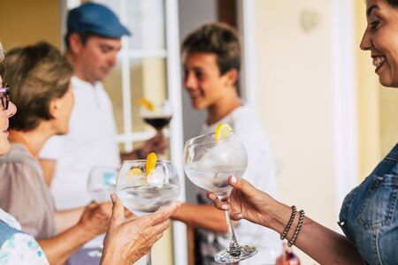 People toasting with glass and cocktails together in friendship - family have fun drinking beverages and smiling - concept of different ages and generations at home during celebrationの写真素材