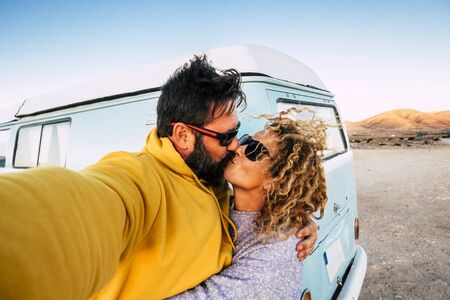 Love and relationship concept with couple of traveler with old vintage van kissing and taking a selfie picture -alternative lifestyle and. vacation with beautiful woman and man outdorの写真素材