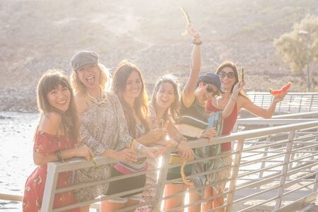 Friends people caucasian young women have fun together in outdoor leisure activity with light and sun in backlight - group in friendship together laughing a lotの写真素材