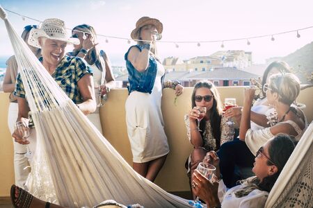 group of women drinking together wine in a glass of cocktail in the terrace of home - friends and ladies celebrating event or party - friendship concept with people having funの写真素材