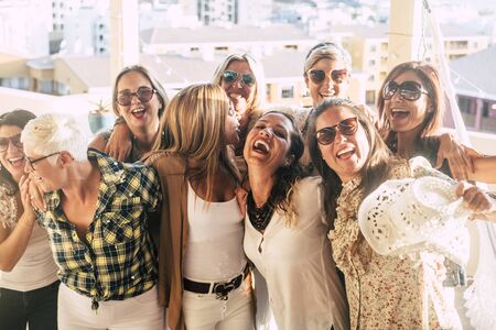 Group of female adult mixed generations people having fun together during party celebration - laughs and smile and cheerful caucasian women together hugging outdoor in friendshipの写真素材