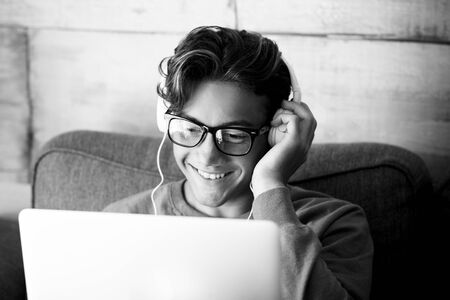 Black and white technoloy indoor activity with cute young teenager people with personal laptop computer and headphones  for music or study speech podcast - modern student lifestyle with internet connectionの写真素材