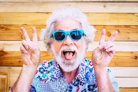 Crazy and fun senior man hippy dressed, white hair and tongue outの写真素材
