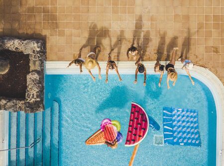 People group of young women have fun in summer holiday at the pool playing with coloured trendy inflatable mattress lilo - viewed from high top aerial - friends enjoy the hotel resort party lifestyleの写真素材
