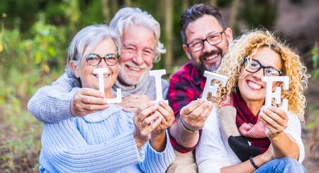 Family group in the forest, four happy people smiling and holding Life wordの写真素材