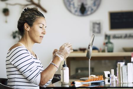Caucasian woman enjoying self made beauty farm and hair style concept at home - hair dye activity during lockdown quarantine with hairstyle stors closed - protection gloves and home active peopleの写真素材