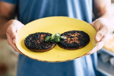 Burned cooked hamburger with chef mistake at home - concept of cook in the kitchen for quarantine leisure indoor activity during lockdownの写真素材